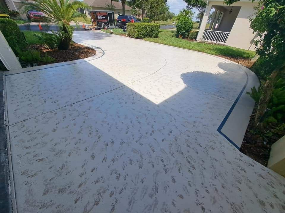 A concrete driveway leading to a house with a car parked in the driveway.