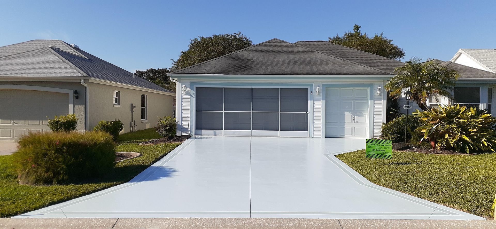 A white house with a gray roof and a white driveway.