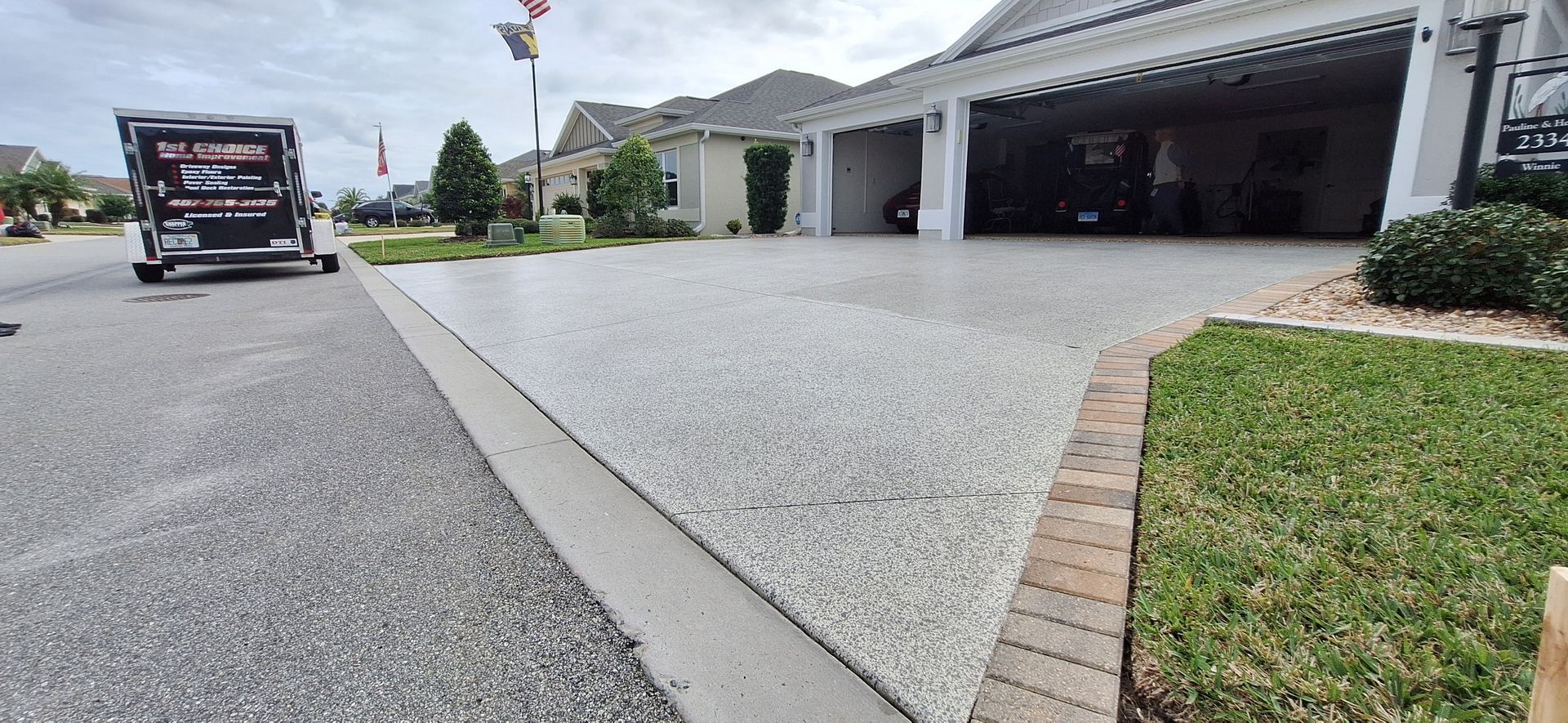 A dog is standing in front of a house with a concrete driveway.