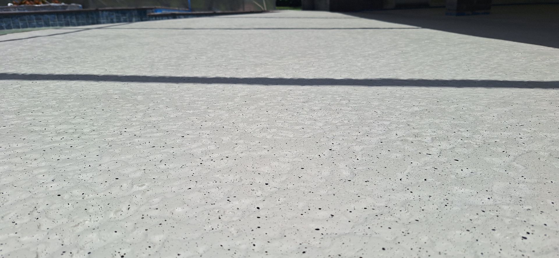 A close up of a concrete driveway next to a pool.