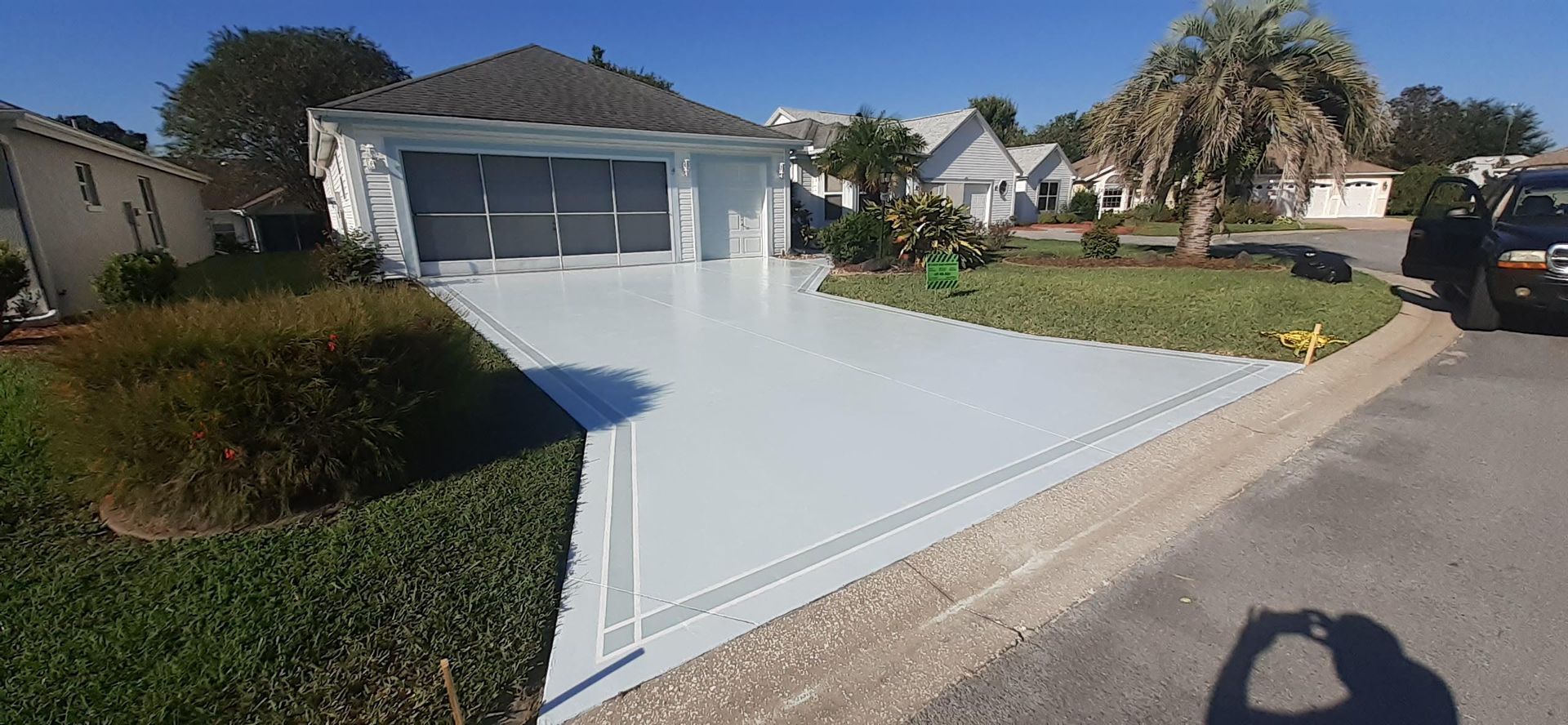 A white car is parked in front of a white house.