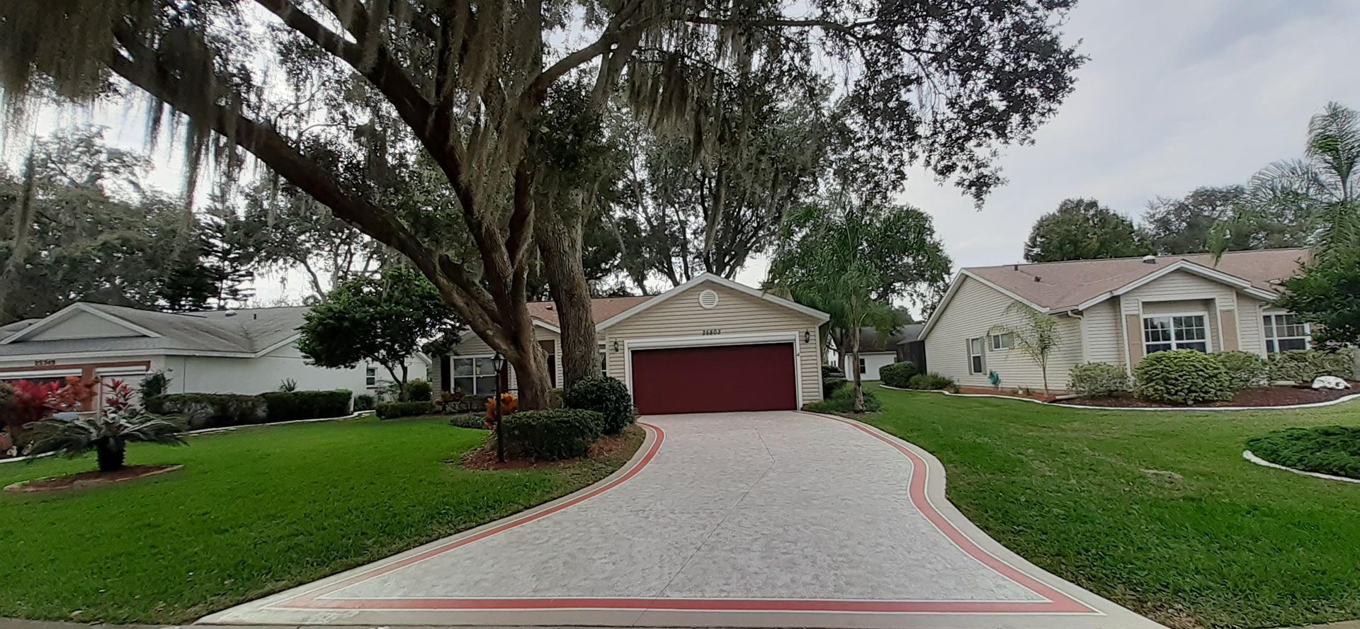 A driveway leading to a house with a red garage door.
