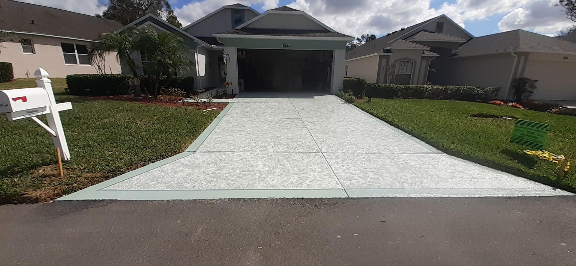 A driveway leading to a house with a mailbox in front of it.
