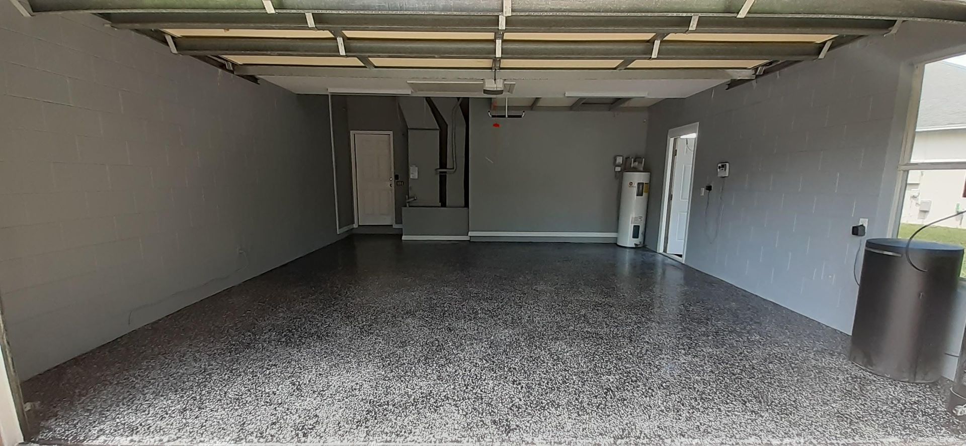 A large empty garage with a gray floor and gray walls.
