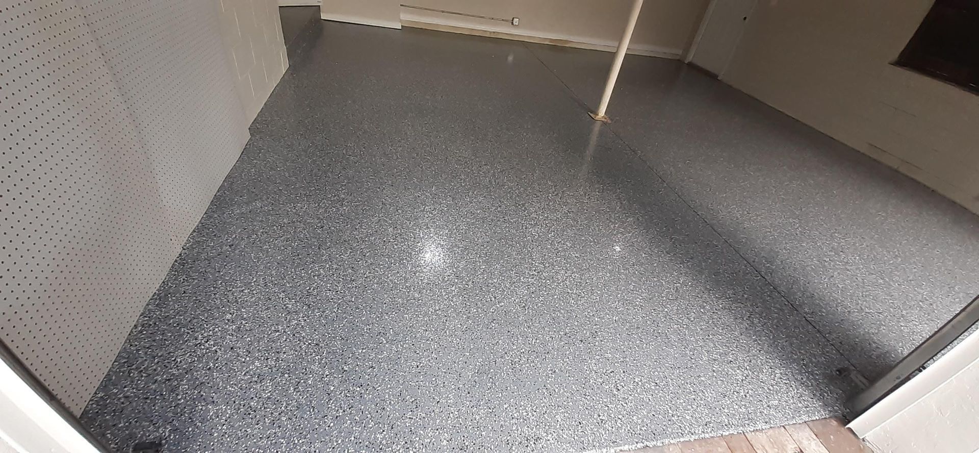 A room with a gray floor and a white wall.