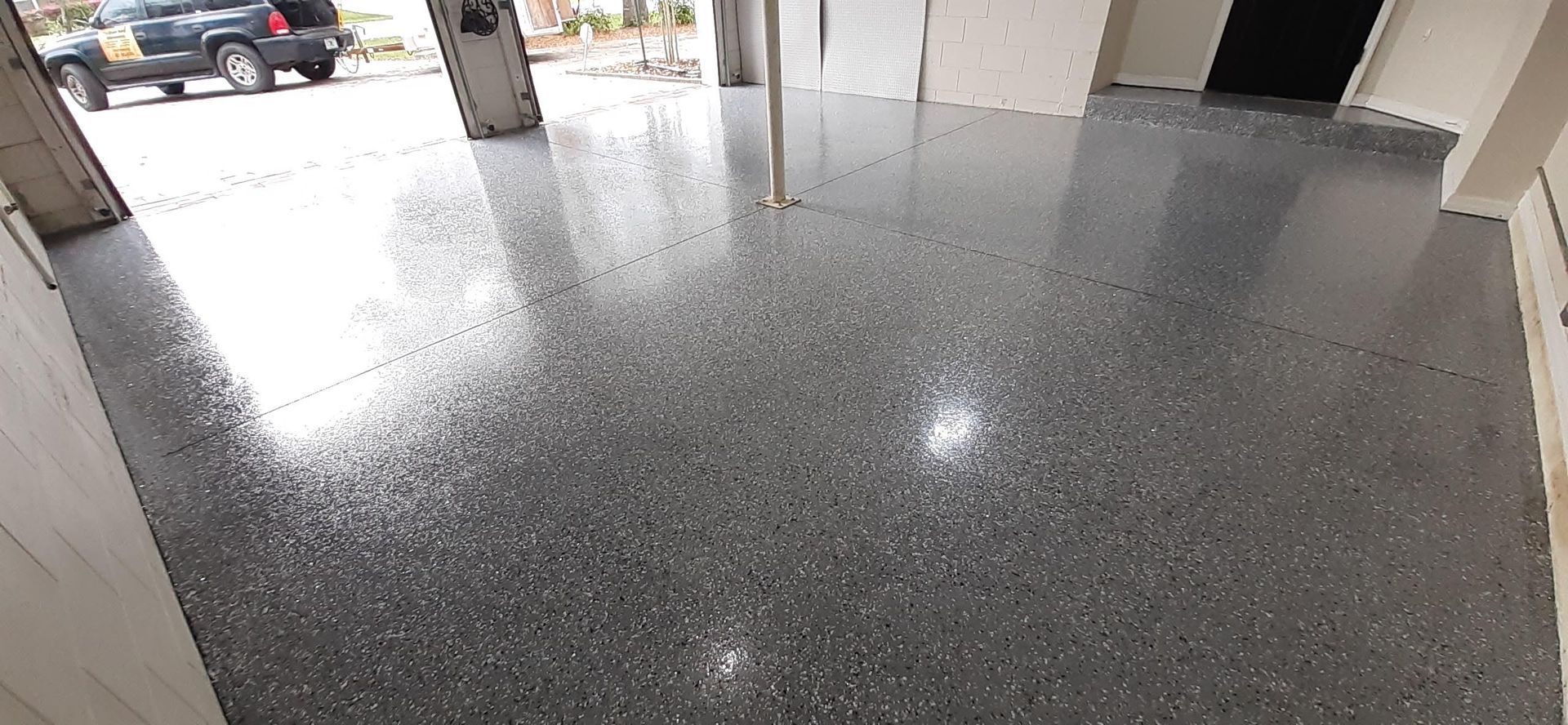 A car is parked in a garage with a shiny concrete floor.