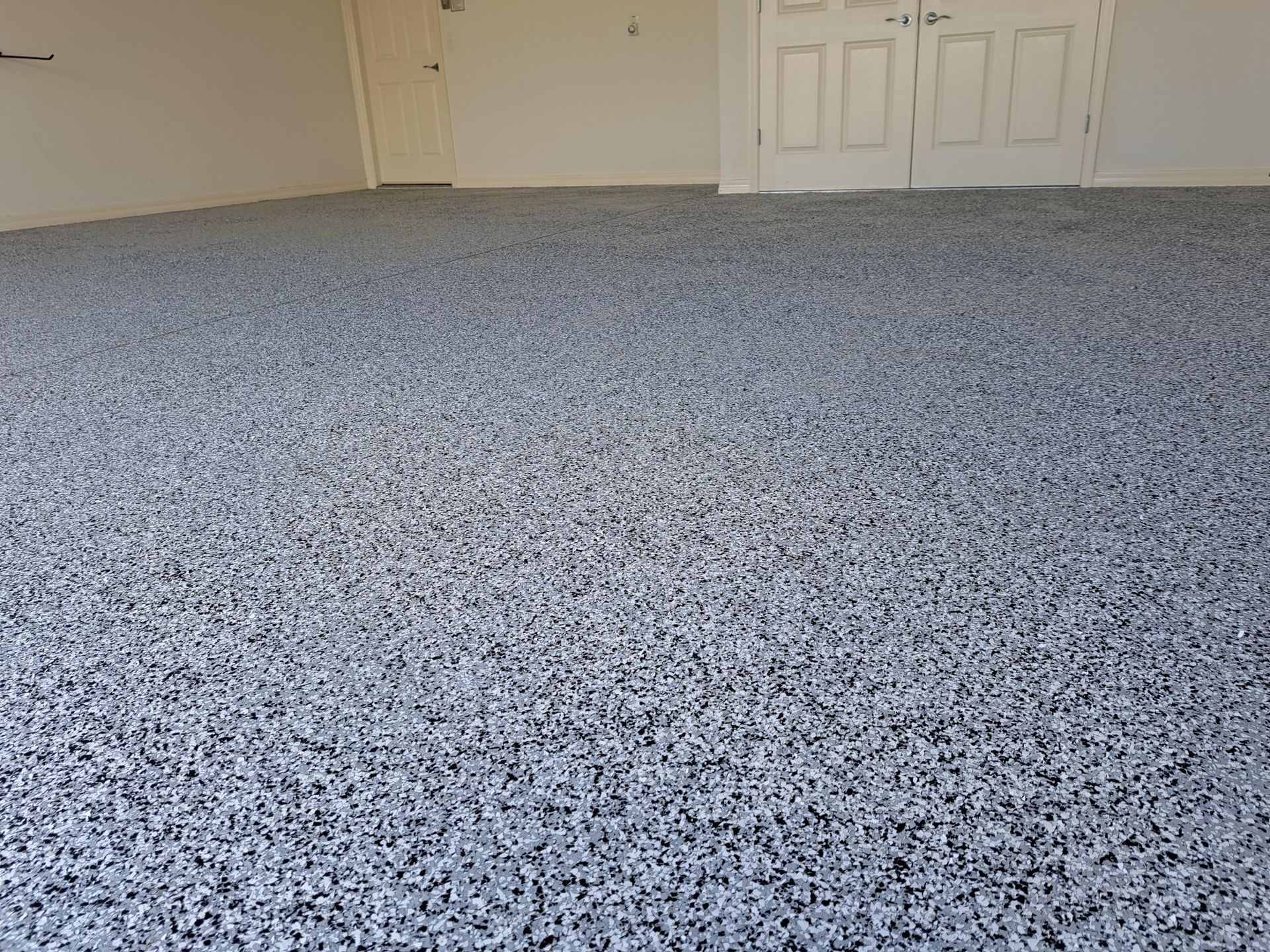 A garage with a gray carpeted floor and white doors.