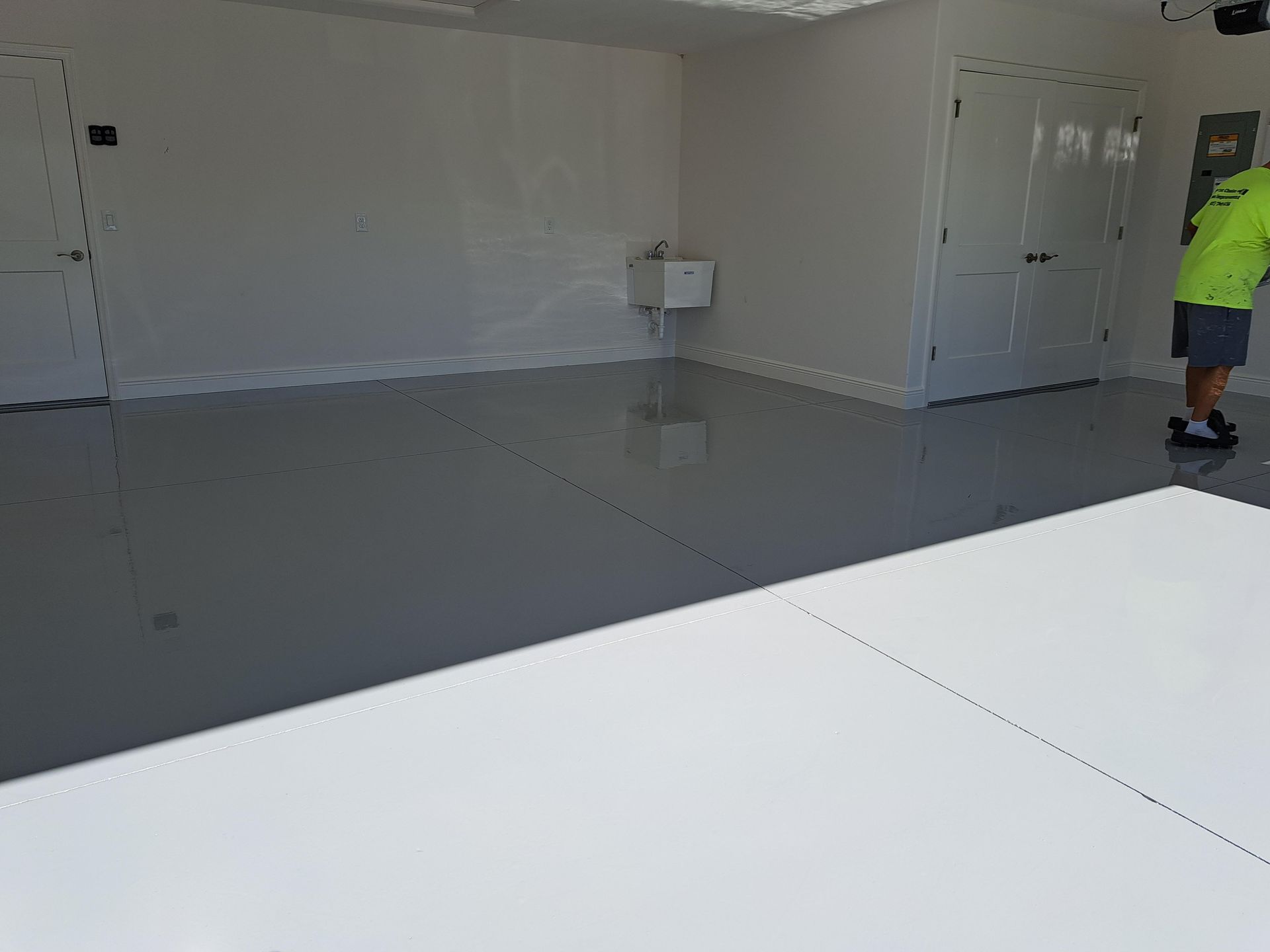 A man is standing in an empty room with a gray floor.