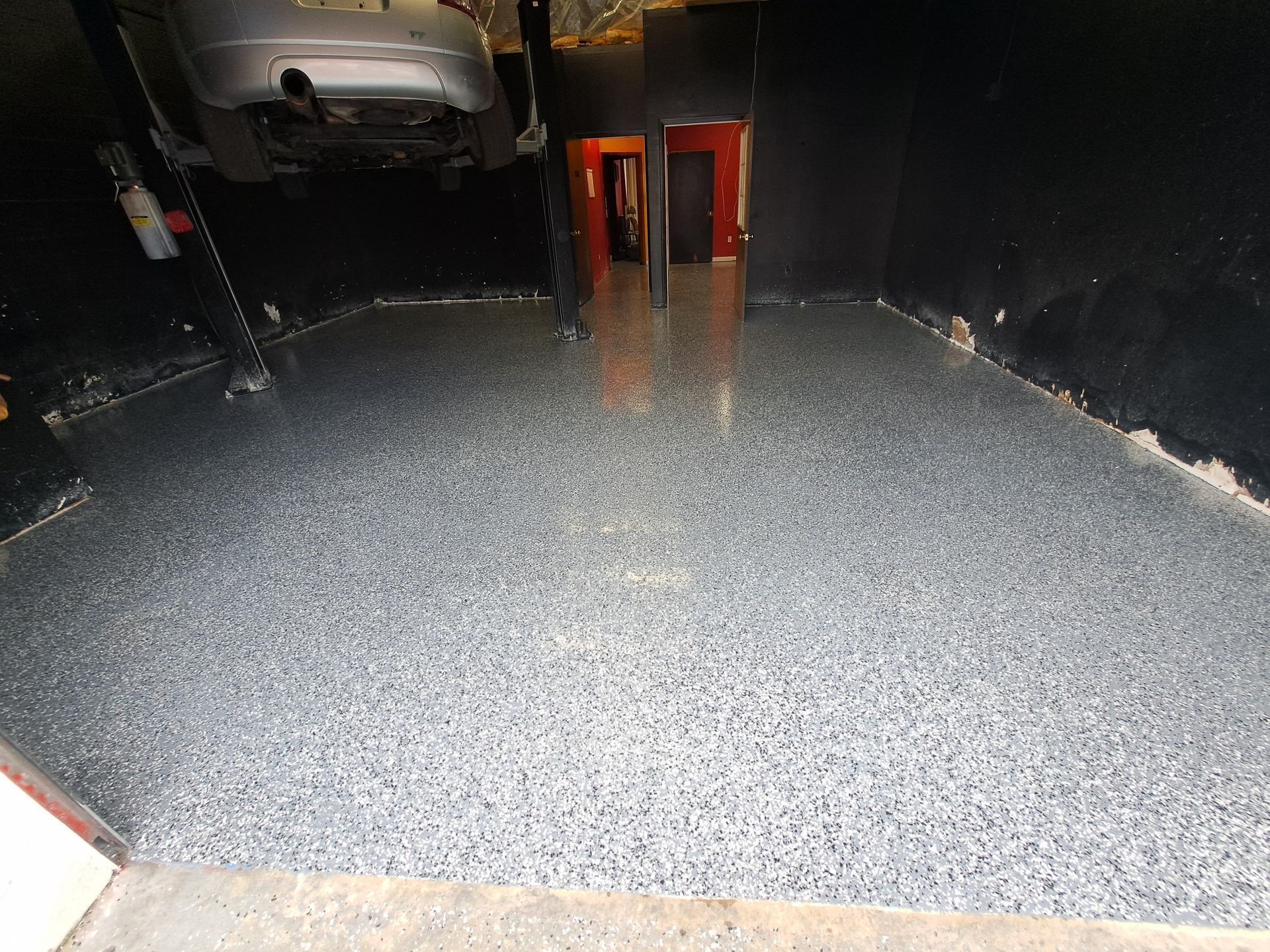 A car is parked in a garage with a gray floor