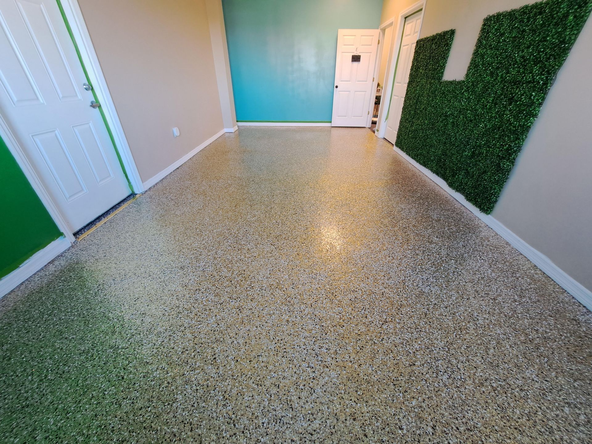 A hallway with a green wall and a concrete floor.