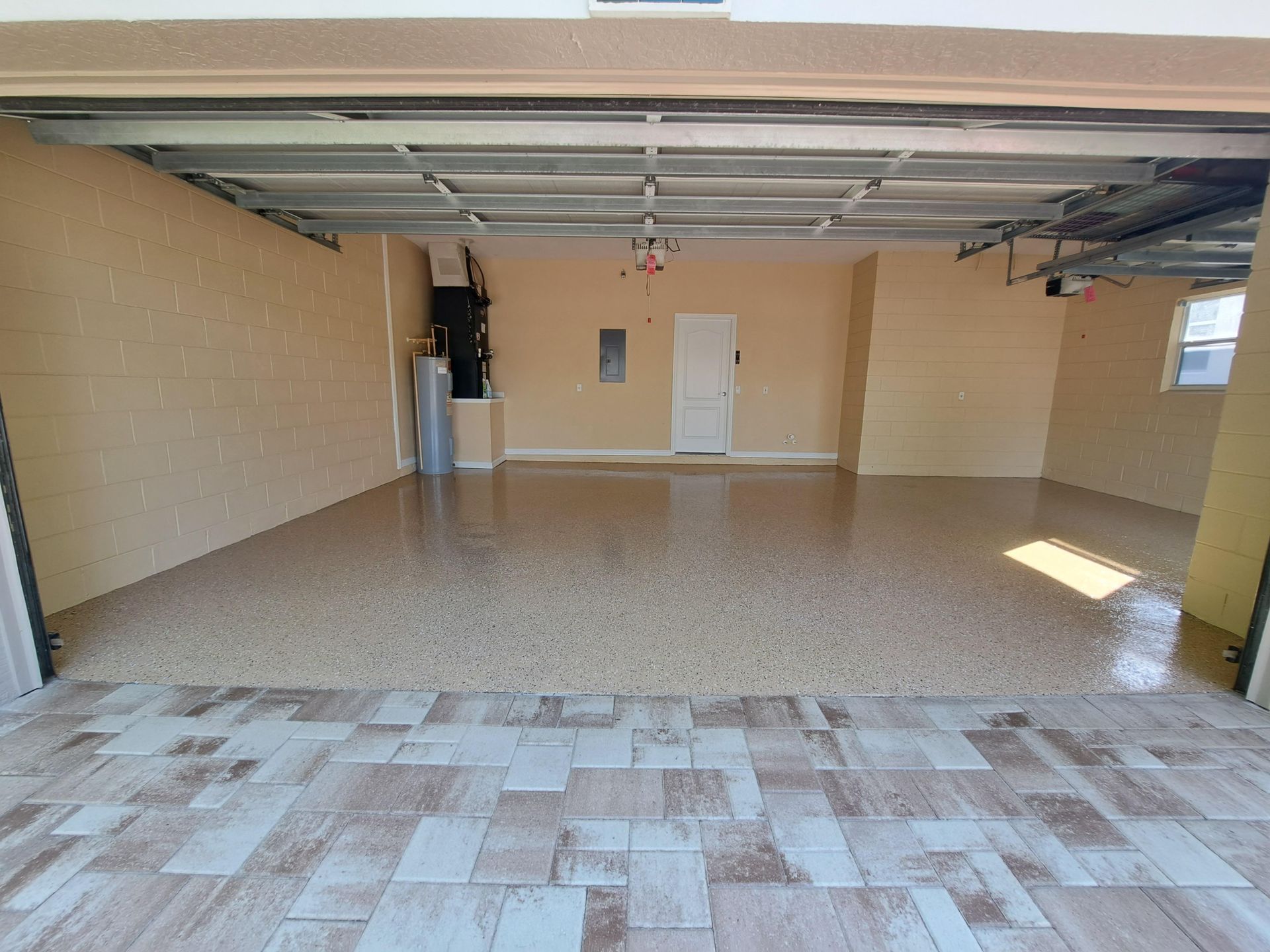 An empty garage with a tiled floor and a garage door open.