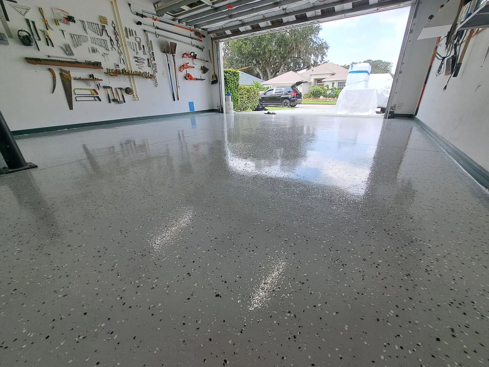 A garage with a lot of tools on the wall and a shiny floor.