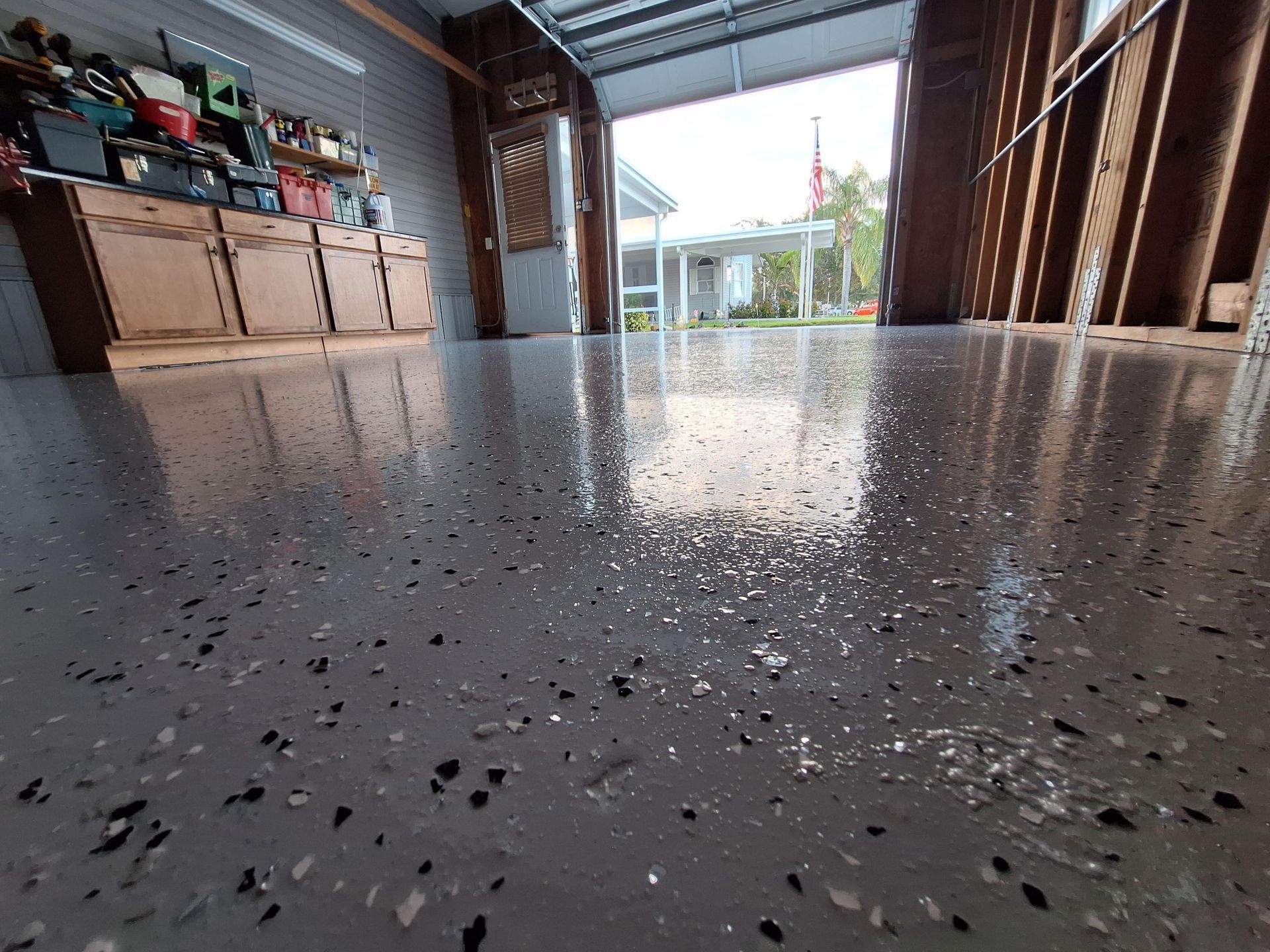 A garage with a shiny floor and a garage door open.
