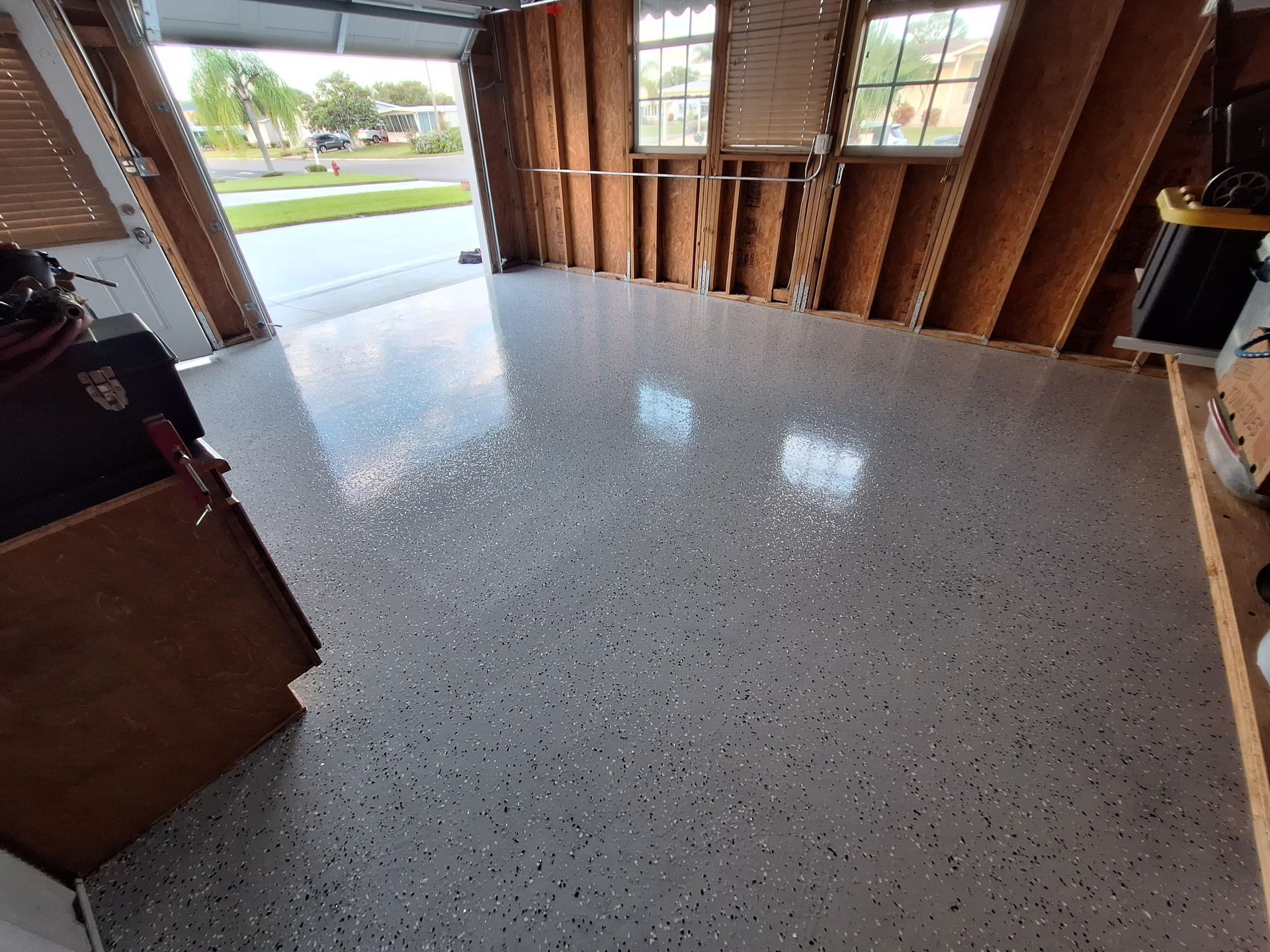A garage with a shiny floor and a garage door open.