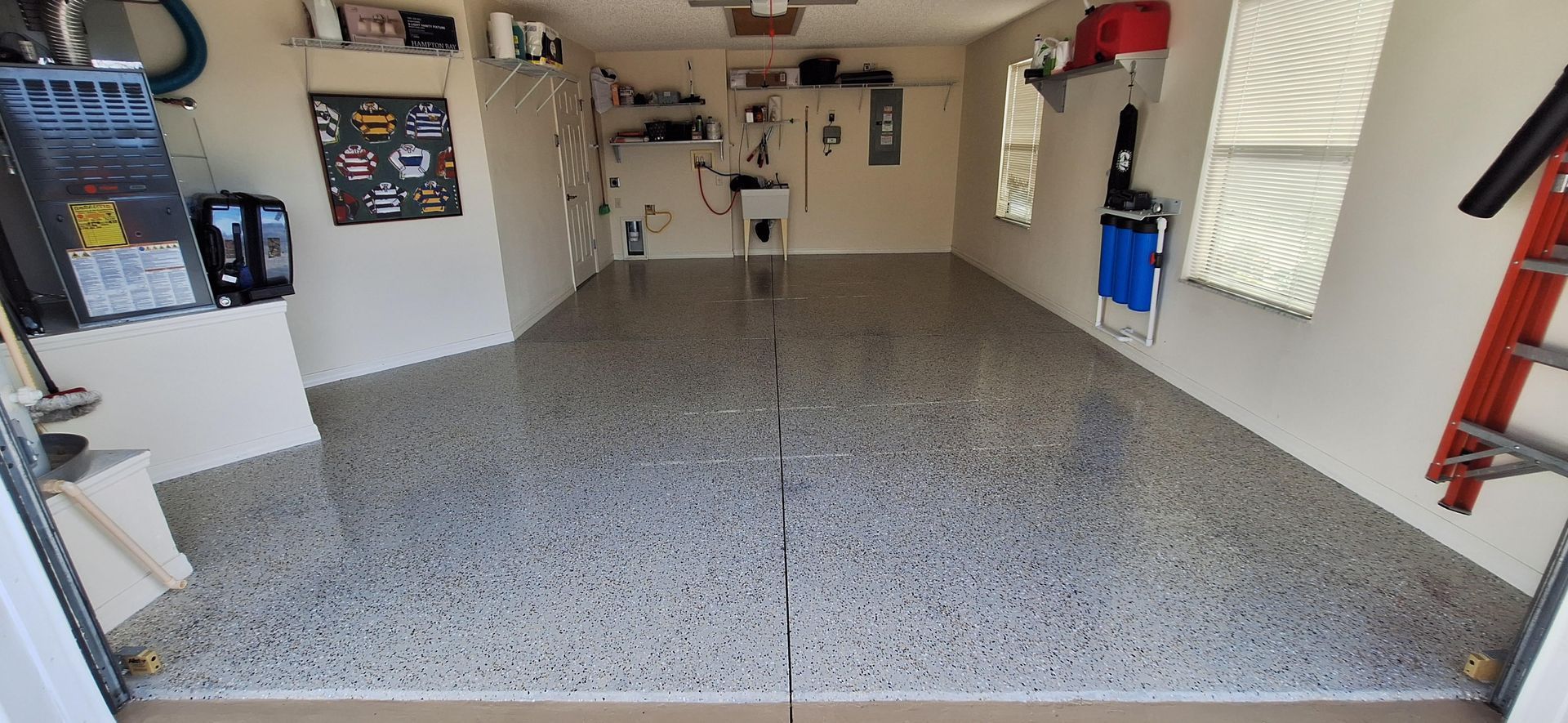 A garage with a ladder in it and a gray floor.