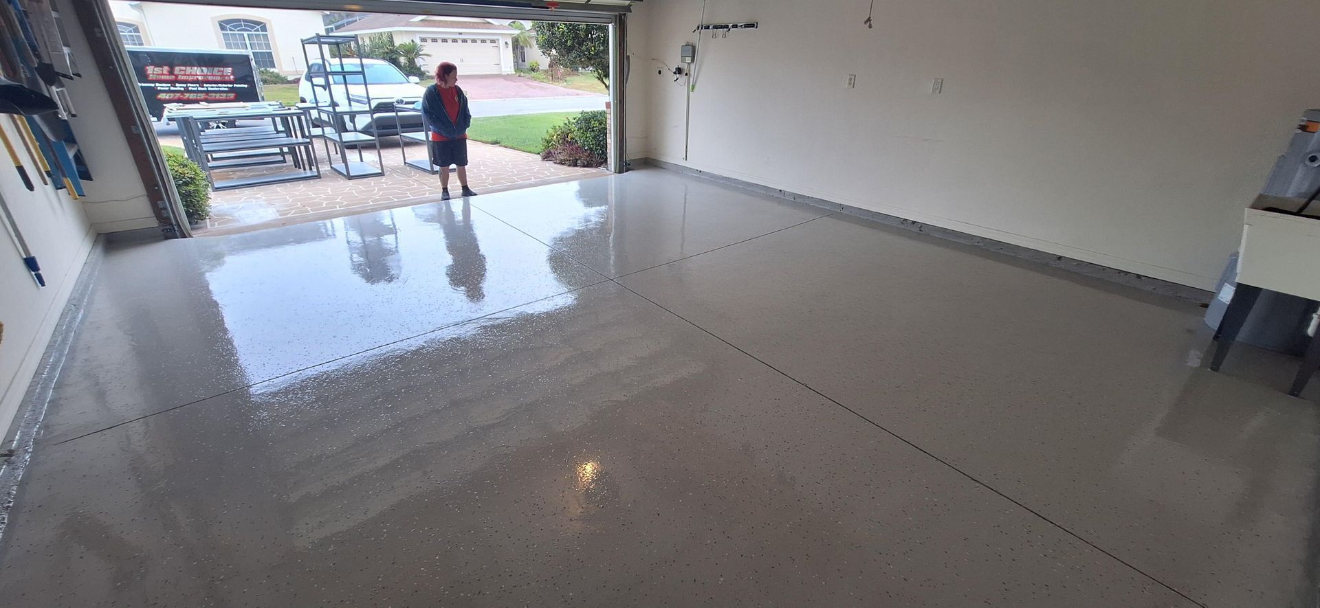 A man is standing in a garage with a shiny floor.