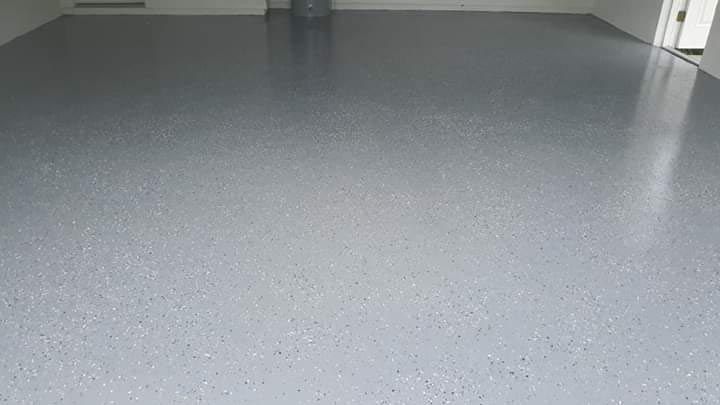 A garage with a gray concrete floor and a white wall.