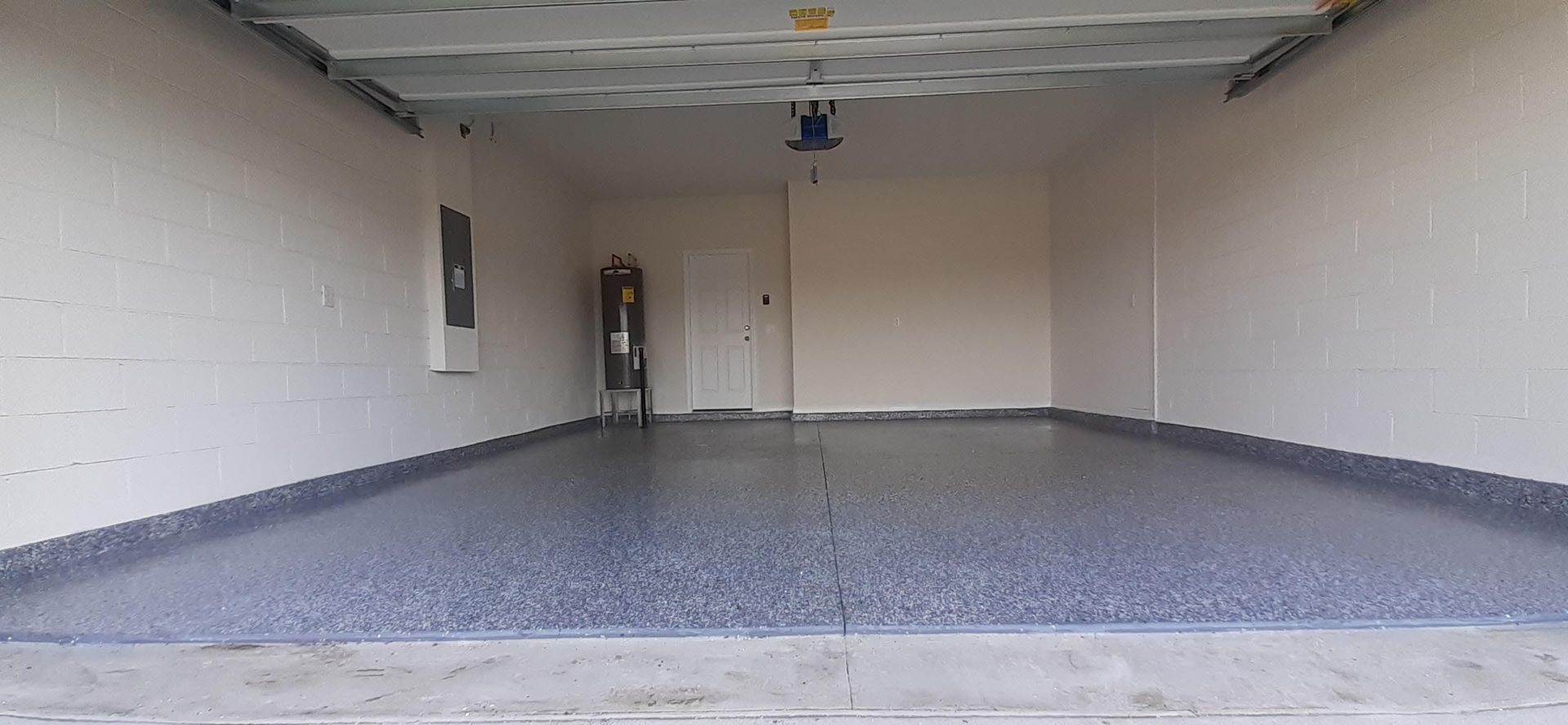 An empty garage with a gray floor and white walls.