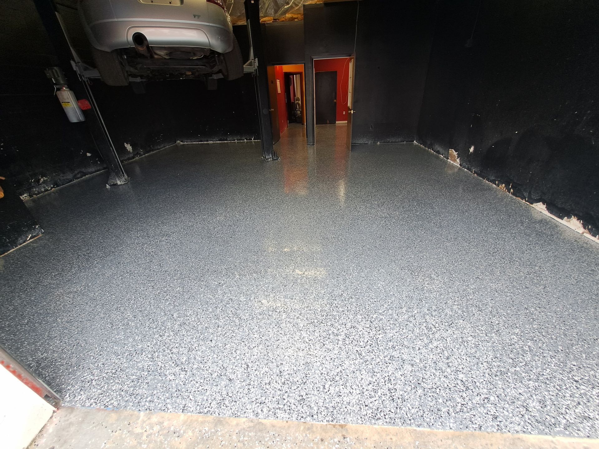 A car is parked in a garage with a gray floor