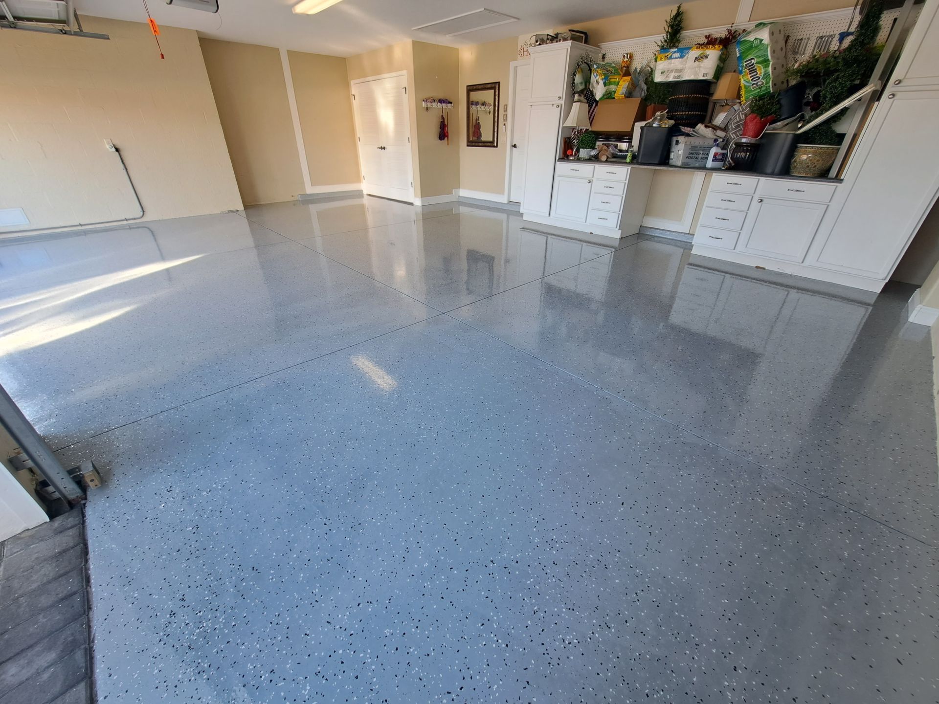 A garage with a shiny gray floor and white cabinets.