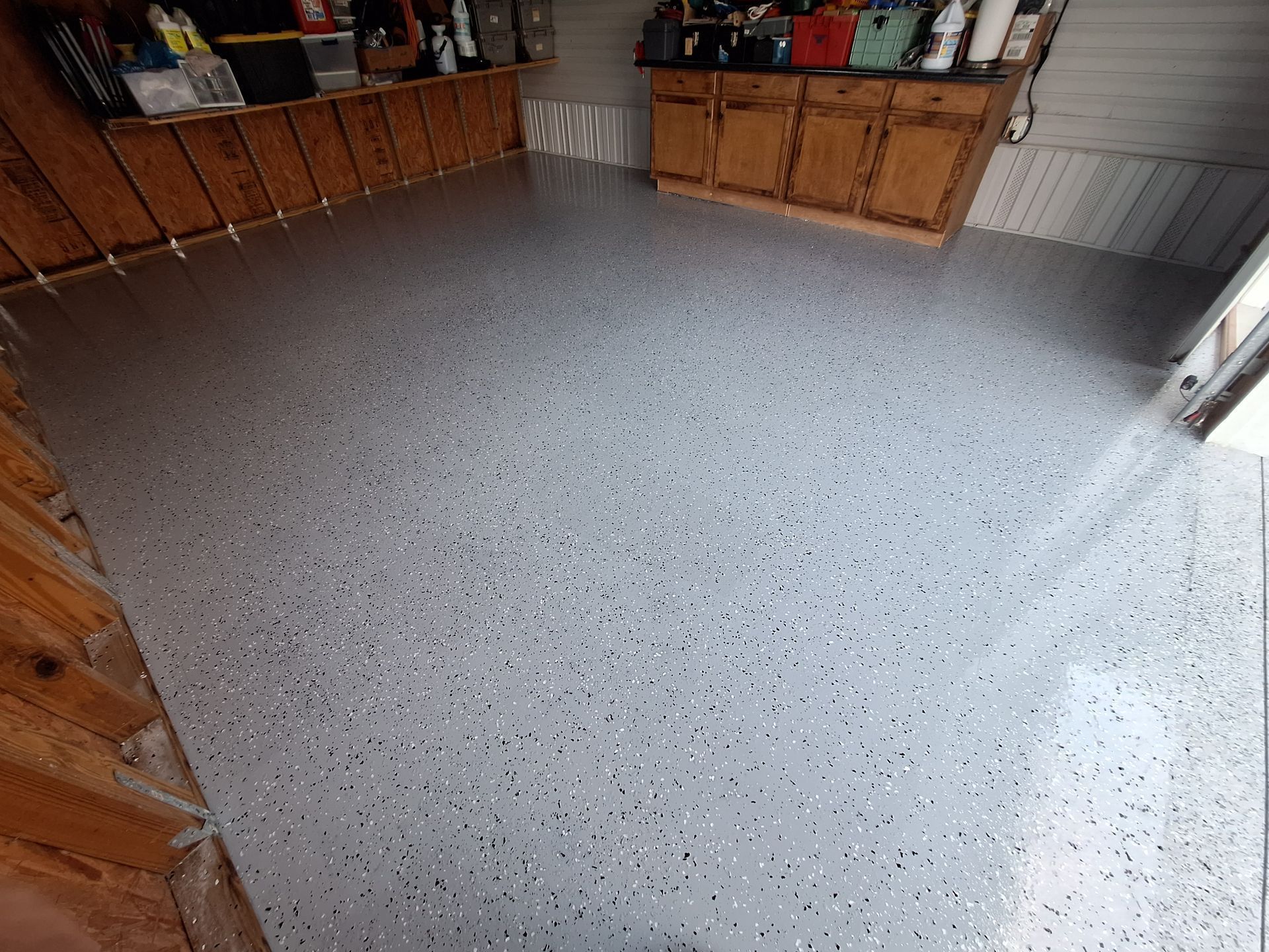A garage with a gray floor and wooden cabinets.