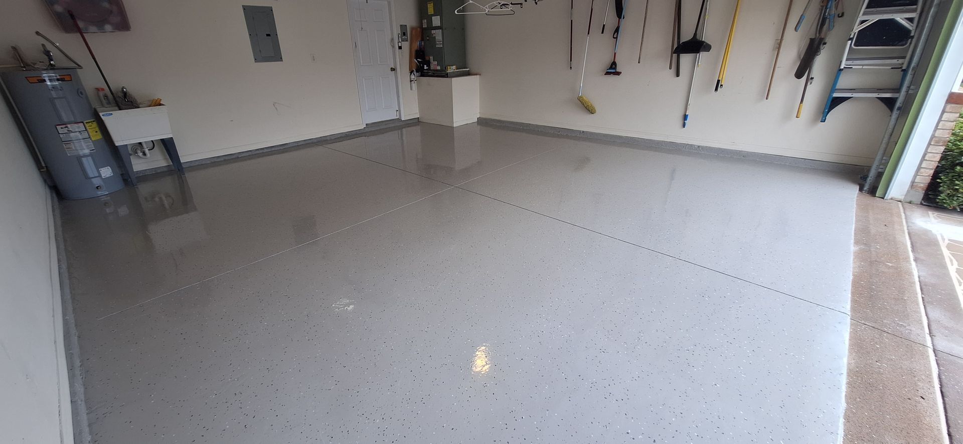 A garage with a concrete floor and a lot of tools on the wall.