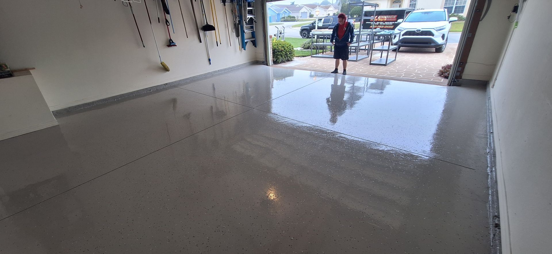 A man is standing in a garage with a shiny floor.