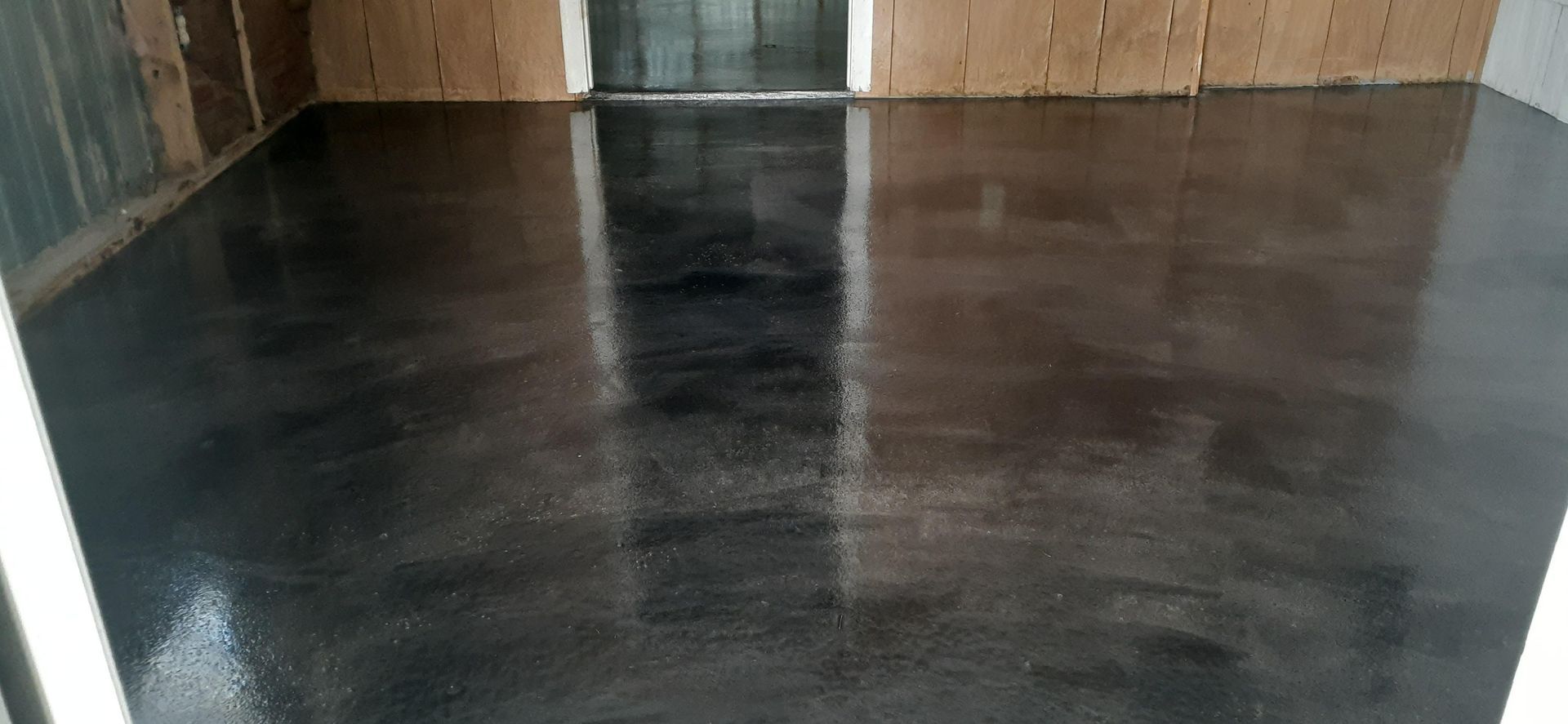 A black concrete floor in a room with a door.