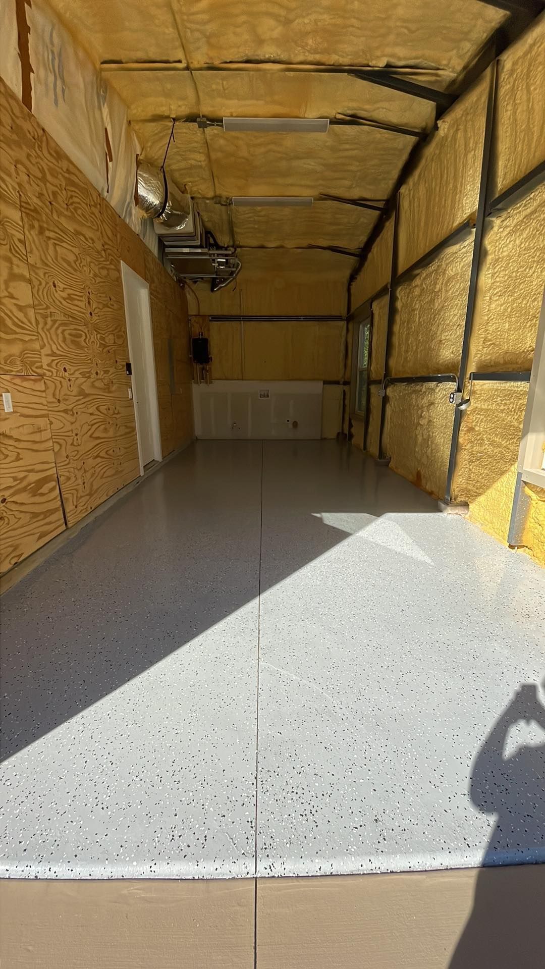 The inside of a garage with a concrete floor and wooden walls.