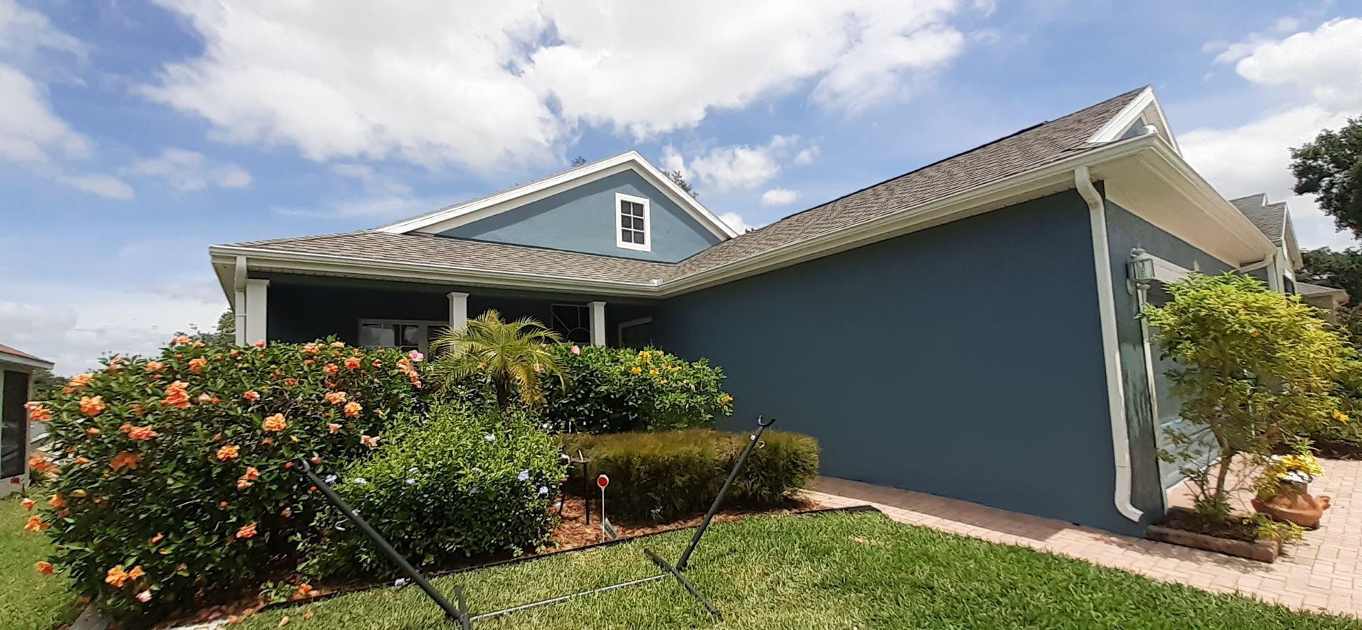 A blue house with a white trim is sitting on top of a lush green lawn.