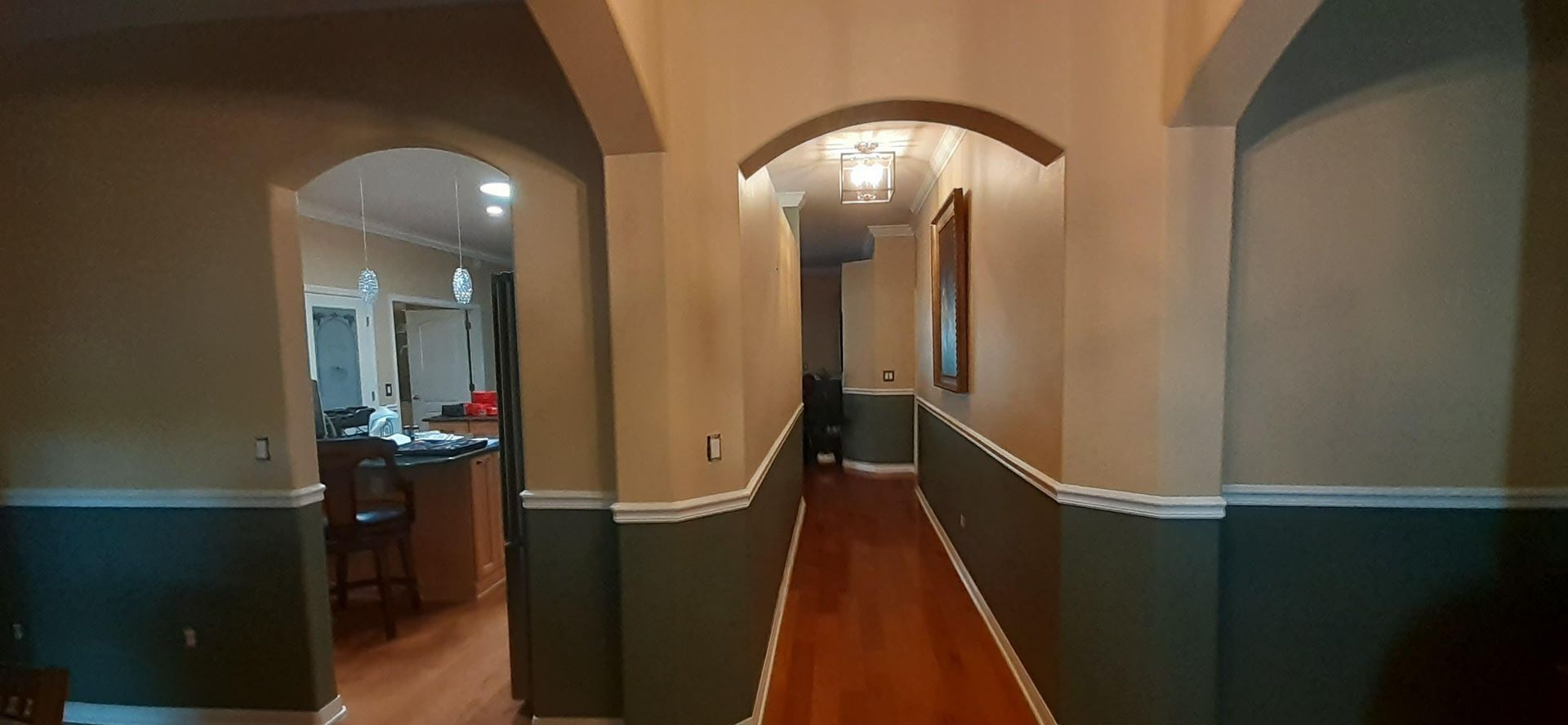 A long hallway leading to a kitchen and dining room in a house.