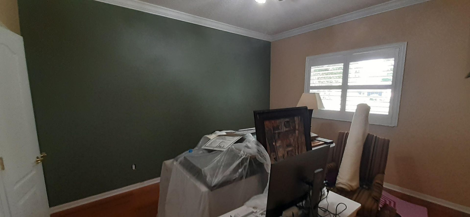 A room with a computer on a desk and a picture on the wall.