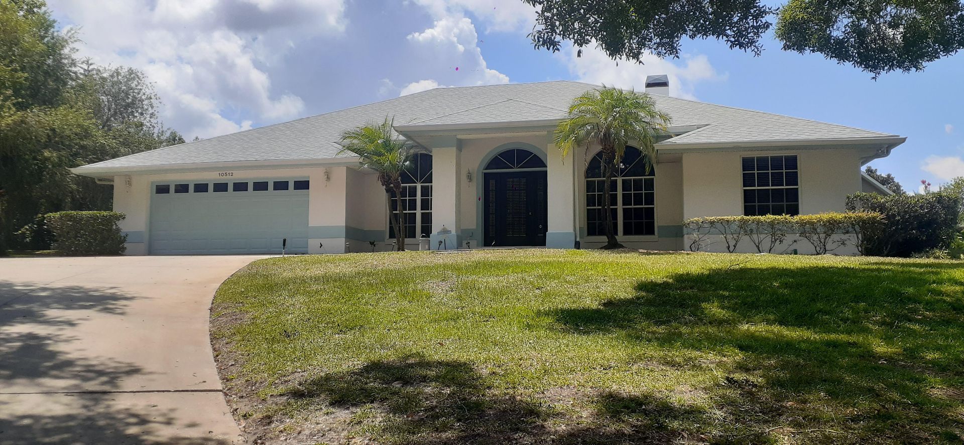 A white house with a white garage door is sitting on top of a lush green lawn.
