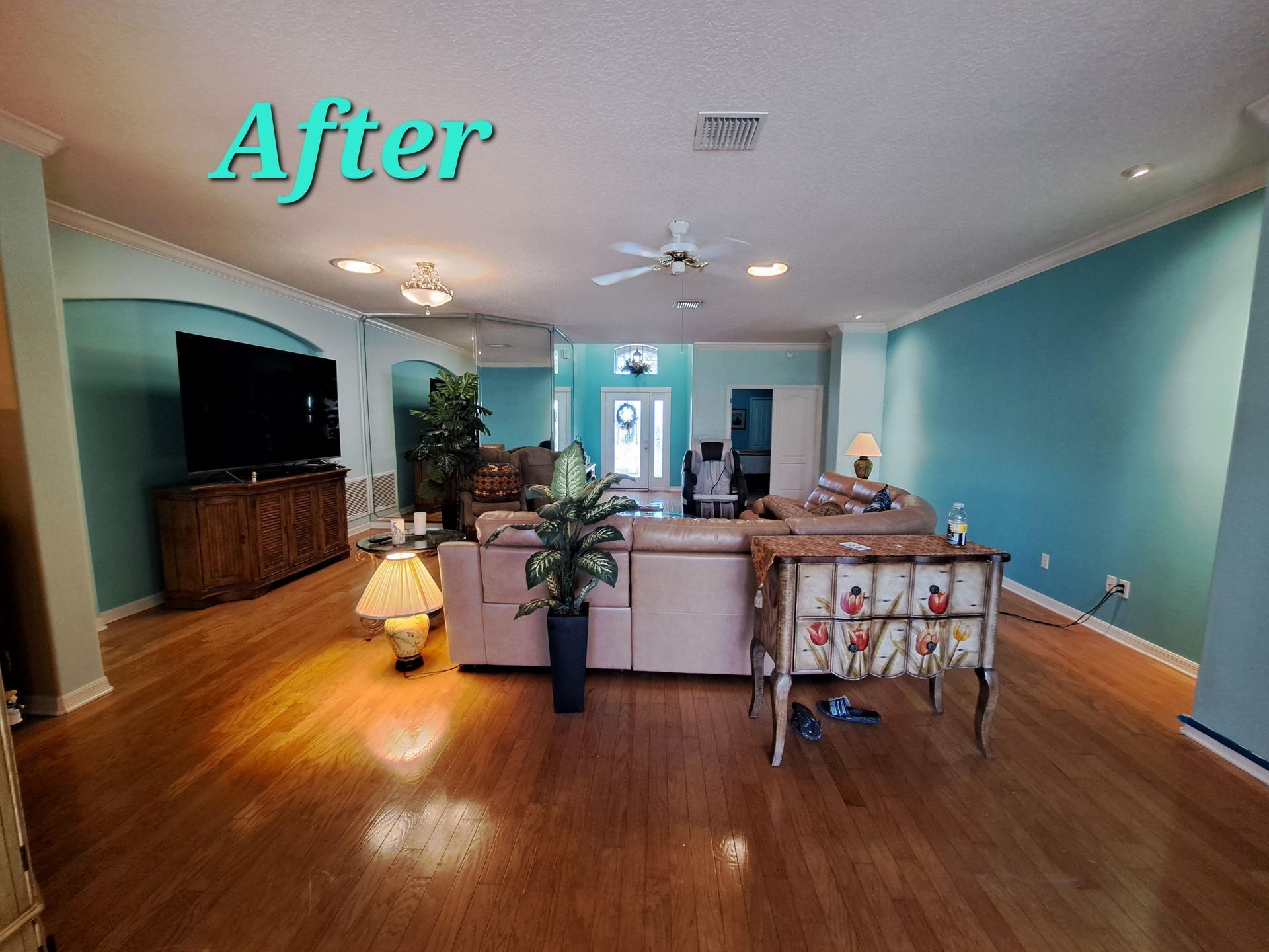 A living room with hardwood floors and blue walls is shown after being painted.