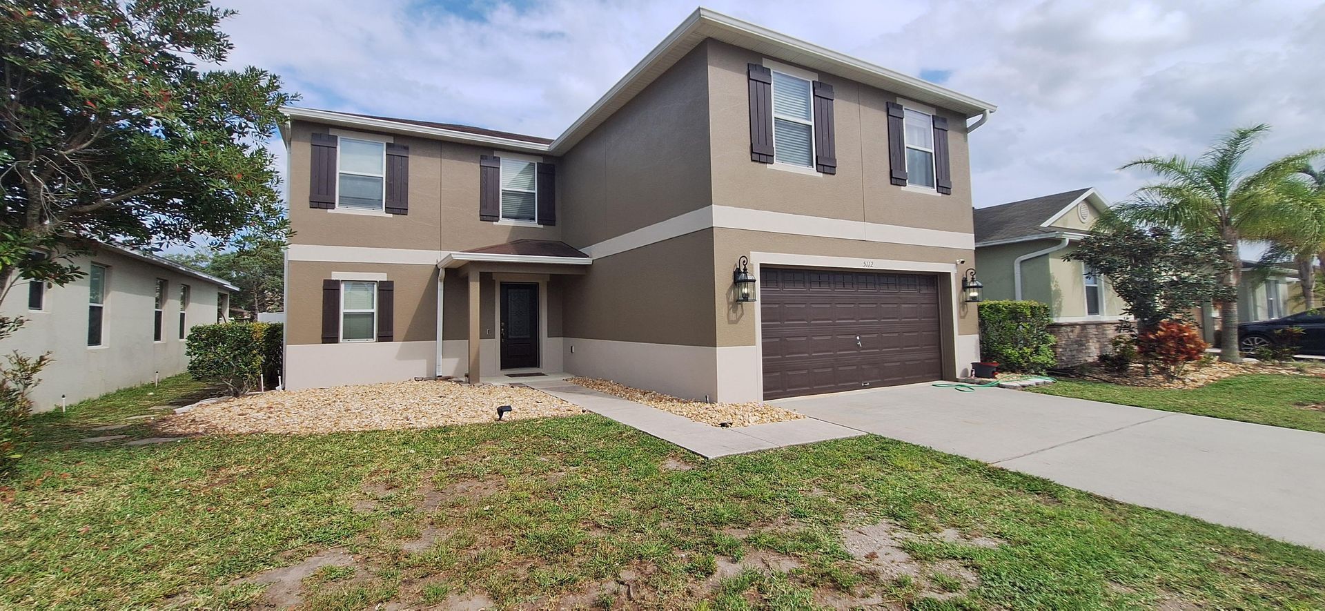 A large house with a brown garage door is for sale in a residential area.