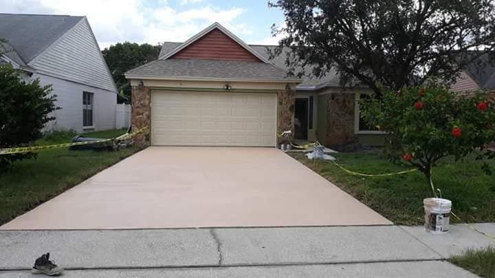 A concrete driveway leading to a house with a garage door.