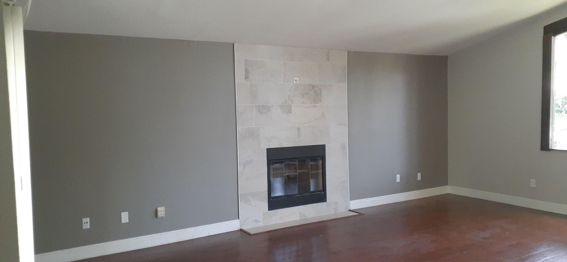 An empty living room with a fireplace and a window.