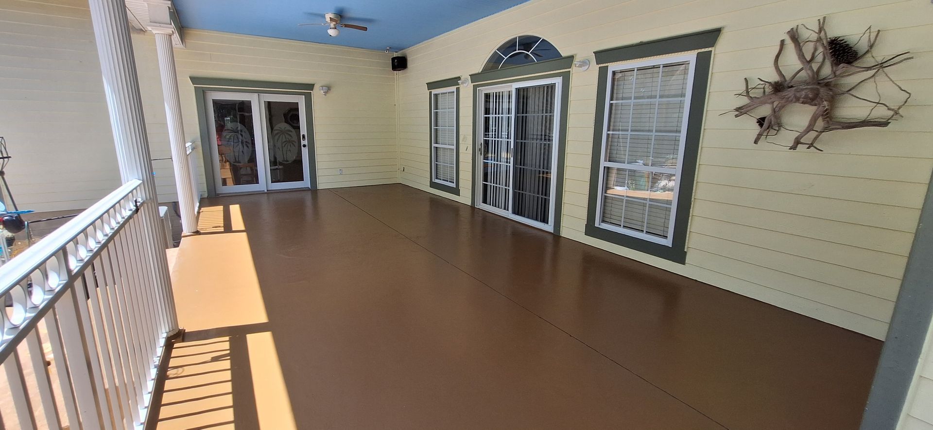 A large porch with sliding glass doors and a ceiling fan.