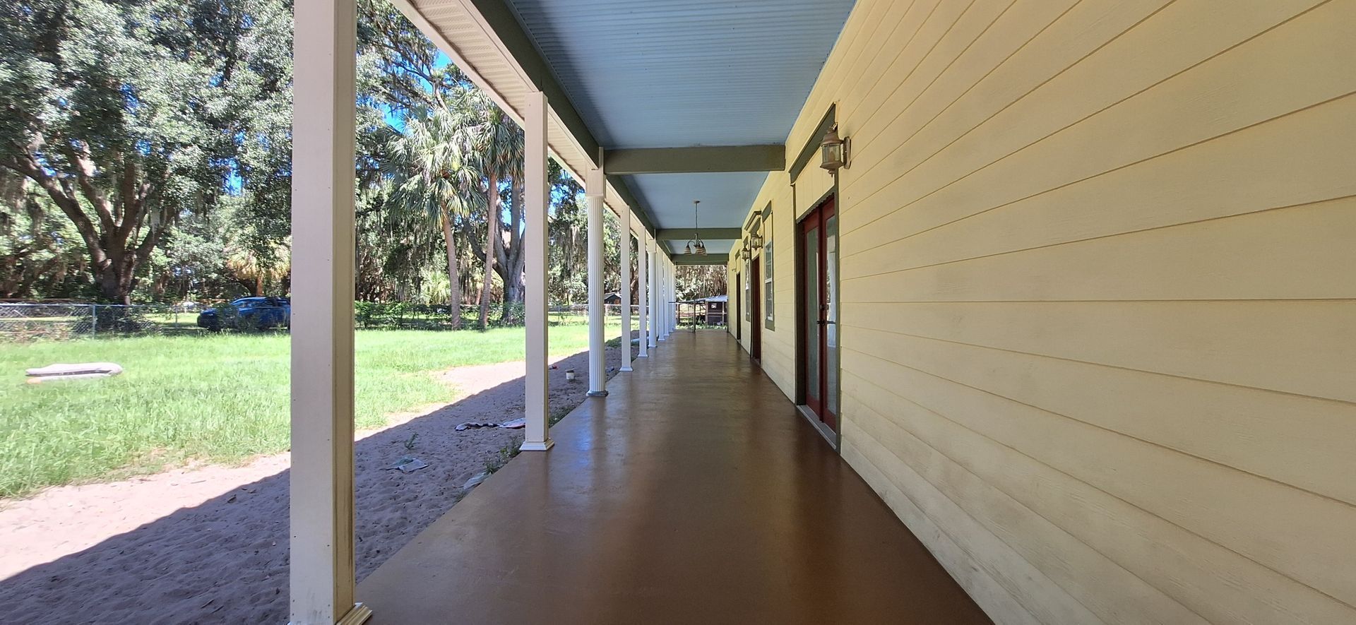 A long hallway with a covered porch and trees in the background.