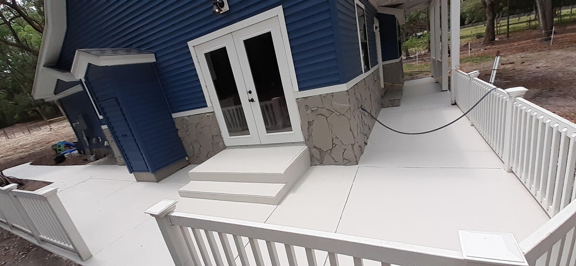 A blue house with a white deck and a white fence.