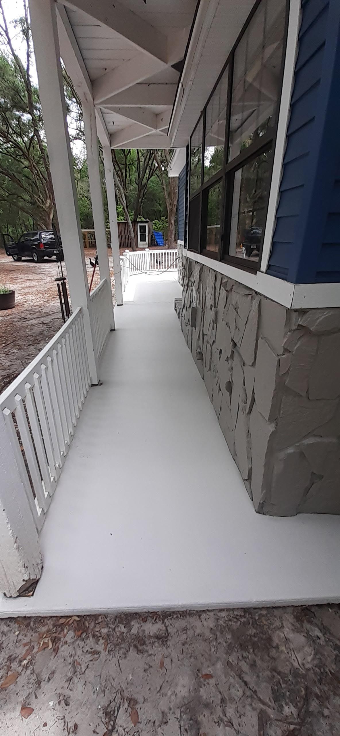 A white porch with a blue house in the background.