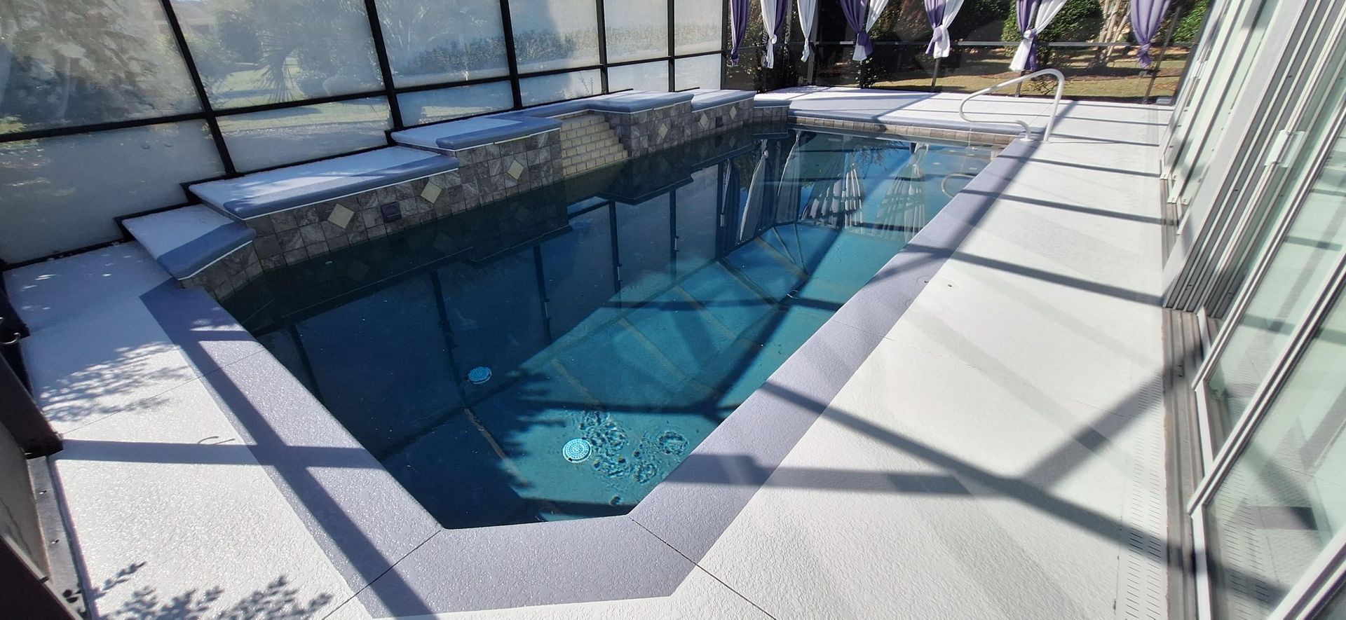 A large swimming pool is surrounded by a glass wall.