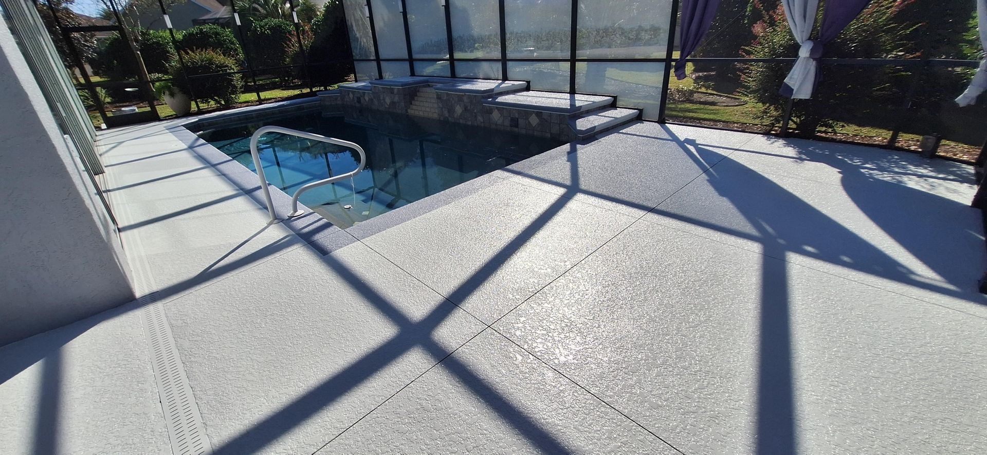 A swimming pool is surrounded by a screened in area in a house.