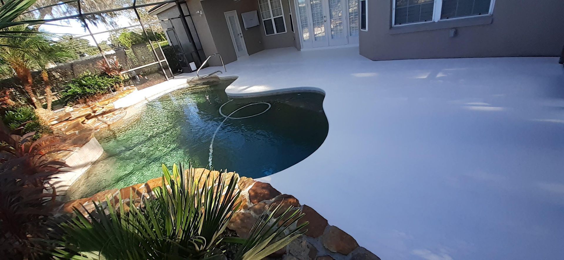 A swimming pool in the backyard of a house covered in snow.
