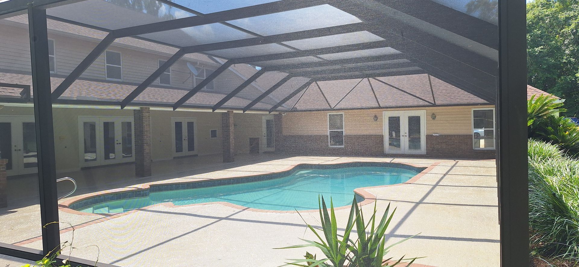 There is a large swimming pool in the backyard of a house.