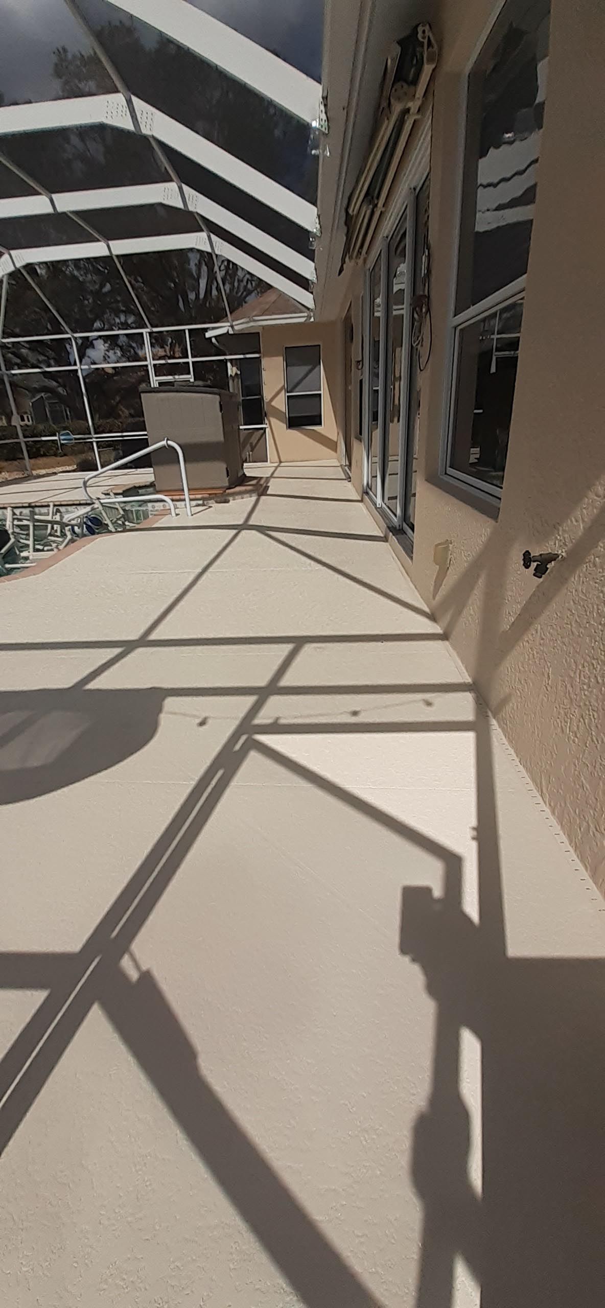 A shadow of a person is cast on a concrete walkway next to a building.