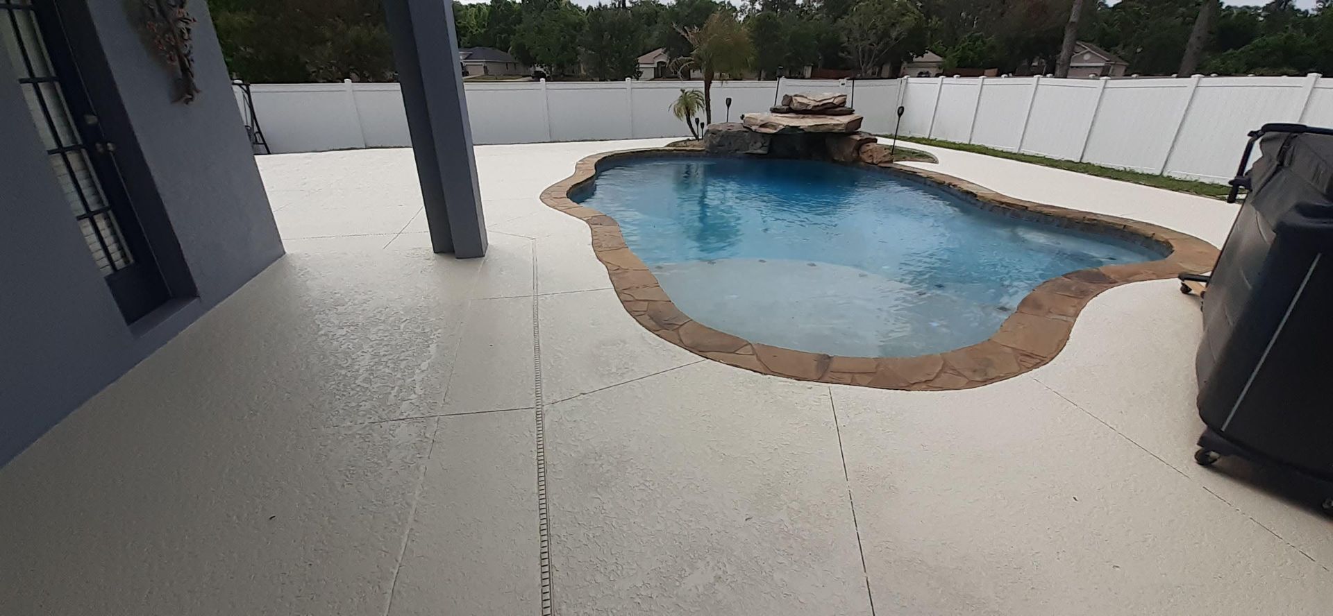 There is a large swimming pool in the backyard of a house.