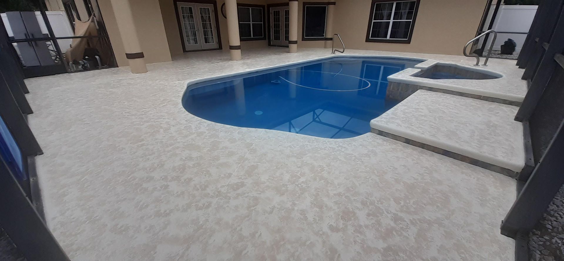 There is a large swimming pool in the backyard of a house.