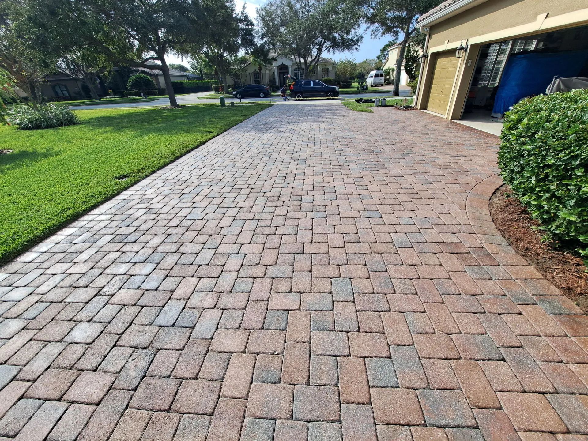 A brick driveway leading to a house with a garage.