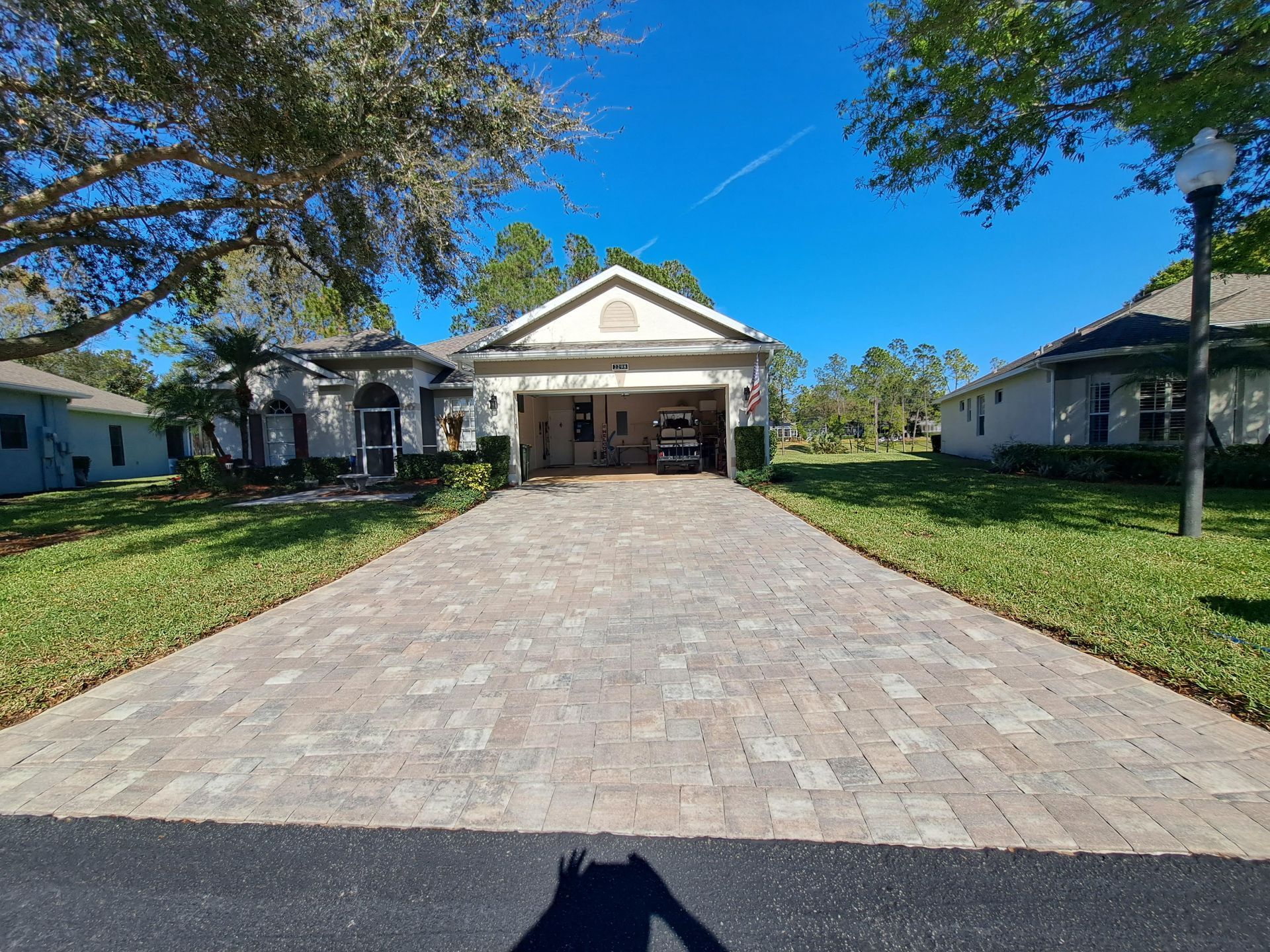 A driveway leading to a house with a car parked in the garage.